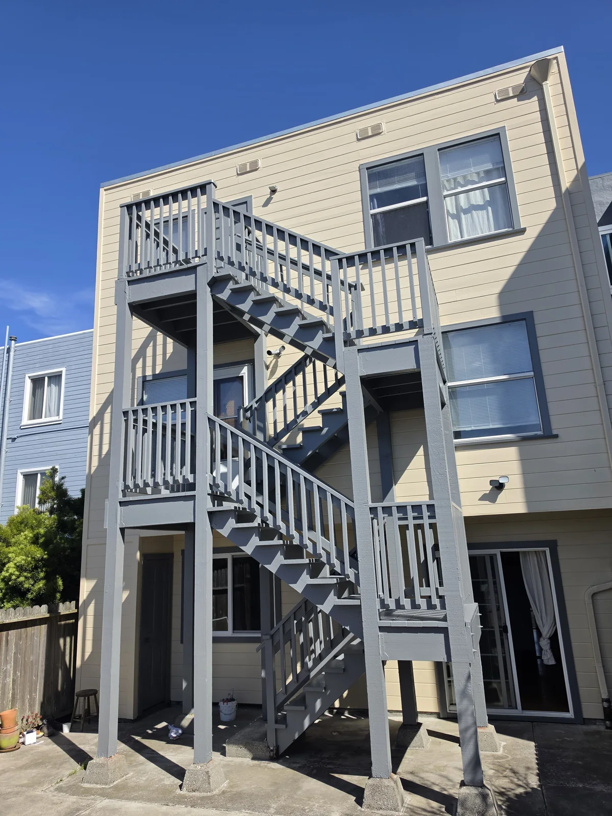 The same back stairs after painting, with fresh gray railings and cream siding