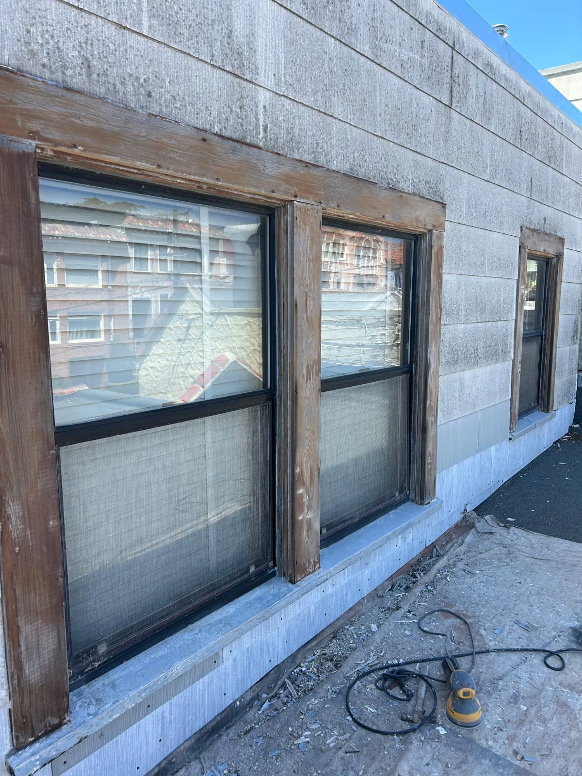 Weathered wood window trim with a sander below